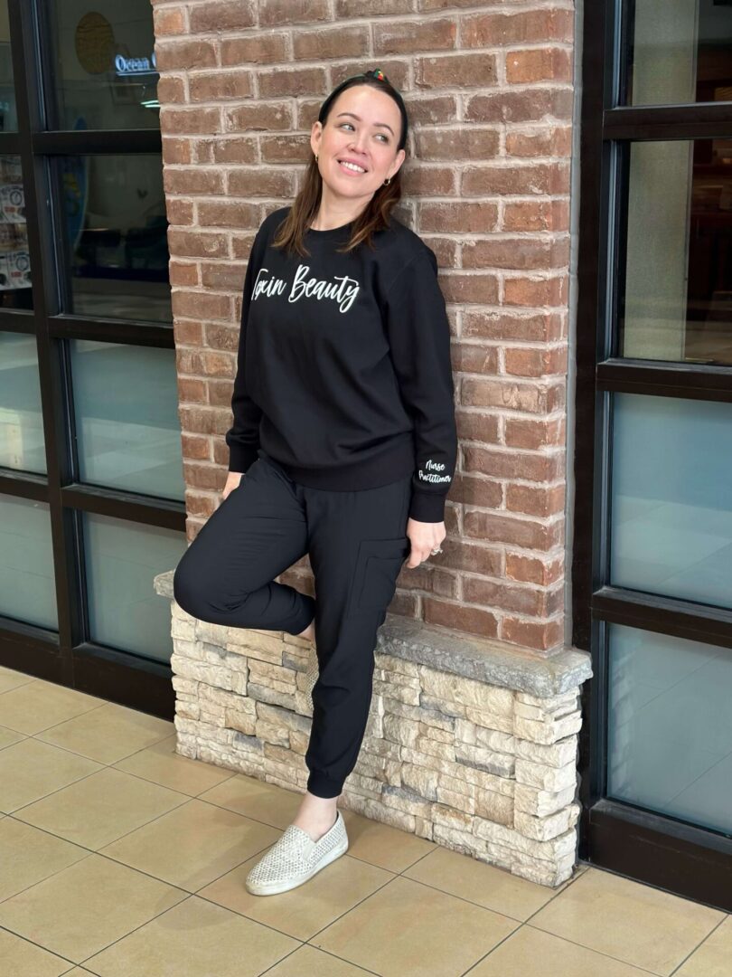 A woman standing in front of a brick wall.